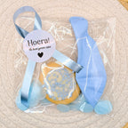Kant-en-klare geboortetraktatie van Mila Trakteert met een blauw geboortekoekje in een cellofaanzakje met blauwe confetti, een blauwe ballon en een sluitsticker met de tekst Een broertje.