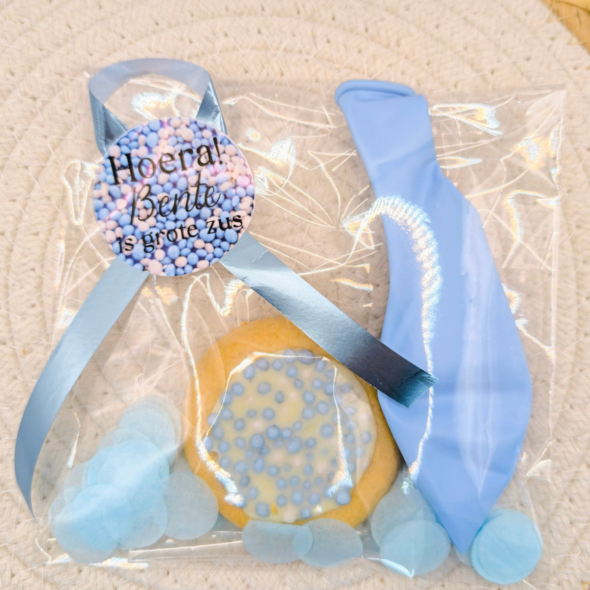 Geboortetraktatie van Milas Trakteert met een blauw geboortekoekje, blauwe ballon en een gepersonaliseerde sluitsticker met de tekst Hoera [Naam broer/zus] heeft een broertje.